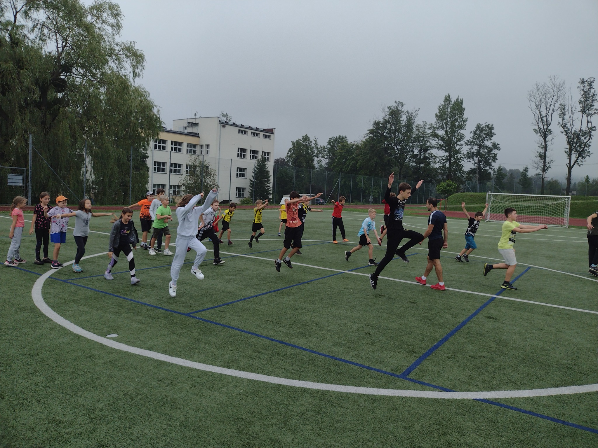 Grupa dzieci i młodzieży w trakcie zajęć sportowych na boisku
