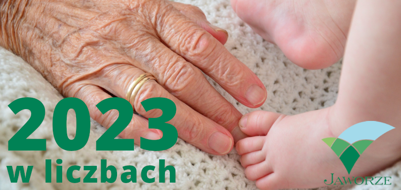 Ręka osoby starszej i noga dziecka, obok napis: 2023 w liczbach