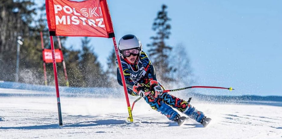 Młody zawodnik jadący na nartach w slalomie gigant