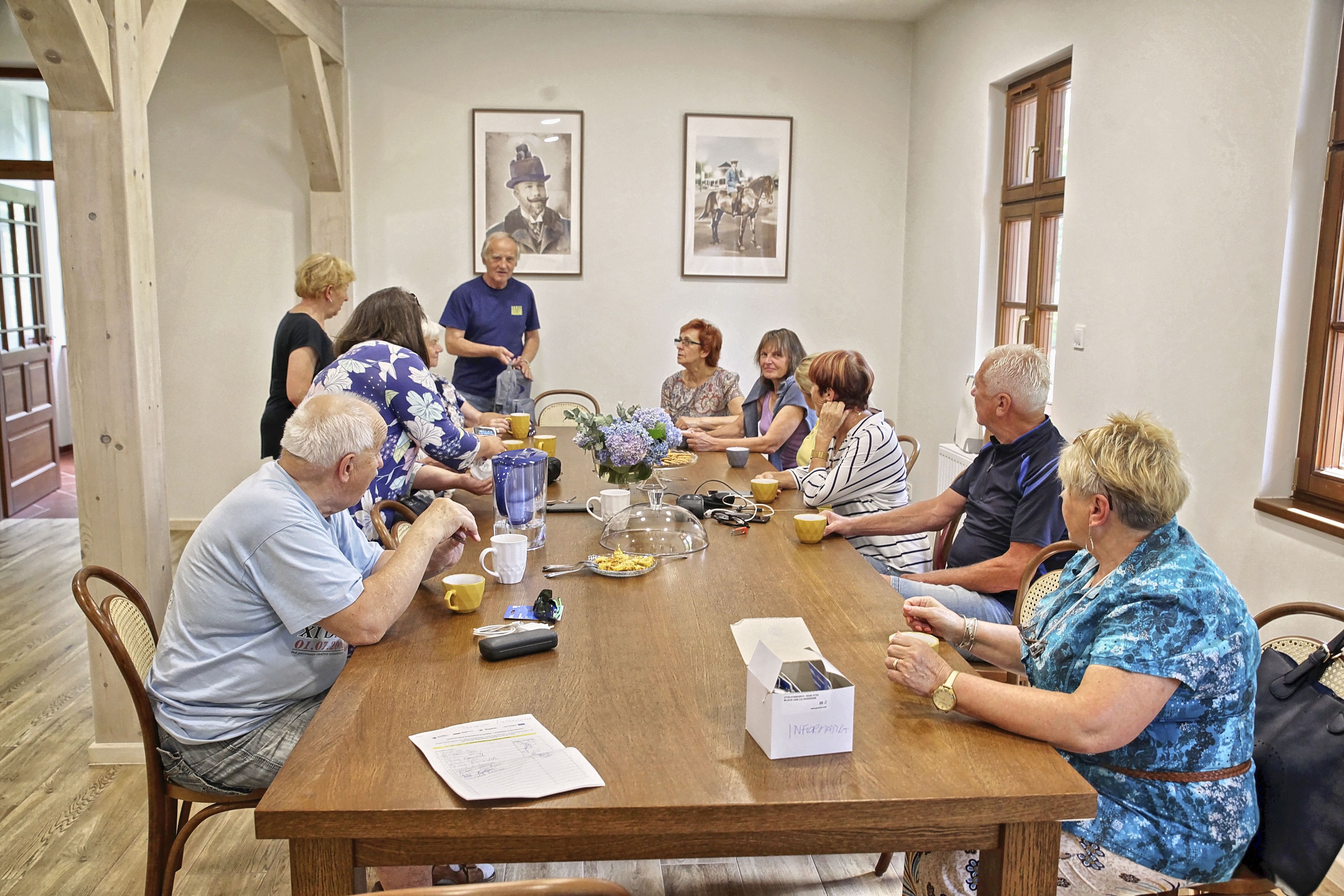 uczestnicy warsztatów podczas zajęć, rozmawiają i siedzą przy wspólnym stole 