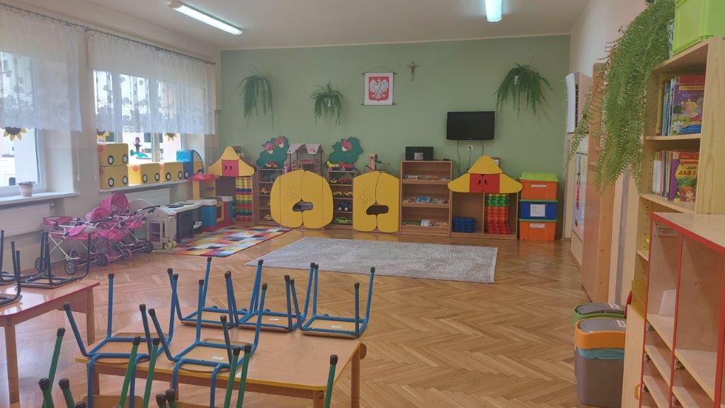 Sala przedszkolna, drewniany parkiet, na ścianie wisi godło Polski