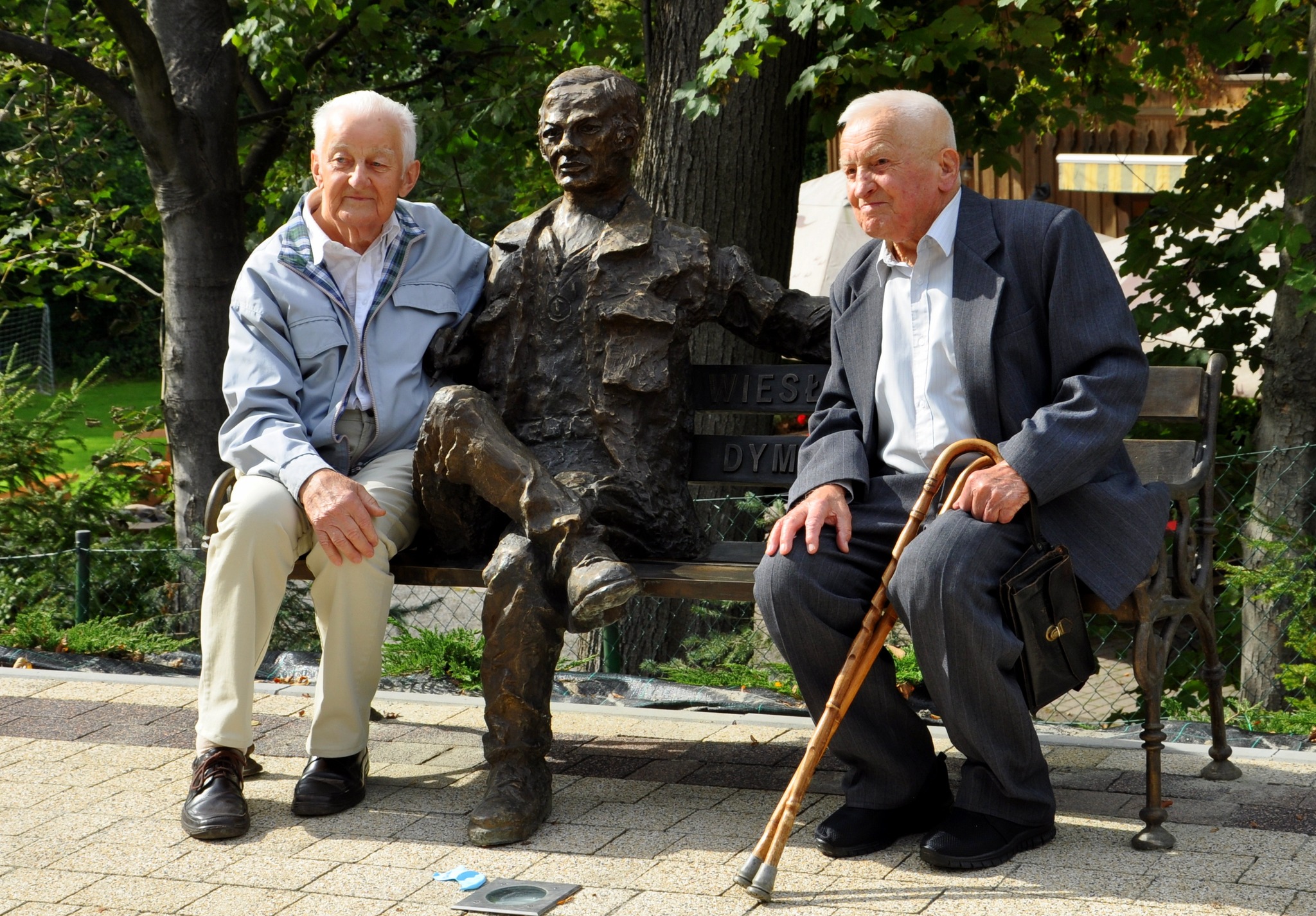 Dwóch starszych mężczyzn siedzących pośrodku postaci-rzeźby