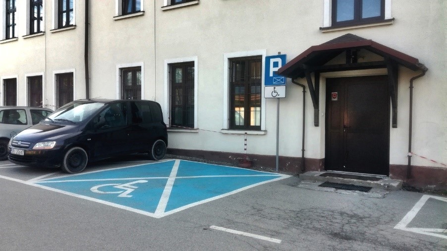 Specjalne miejsce parkingowe dla osób z niepełnosprawnościami oraz wejście z tyłu budynku, od strony parkingu